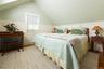 Bedroom with radiator, a wainscoted wall, light wood finished floors, and vaulted ceiling