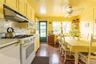 Kitchen featuring white appliances, under cabinet range hood, ornamental molding, a ceiling fan, and brick patterned floors