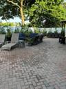 Expansive paver patio featuring a herringbone pattern, mature trees, and a privacy fence