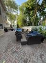 Spacious brick paver patio featuring a swimming pool, privacy fencing, and mature trees