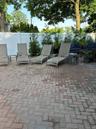 Expansive paver patio with a white privacy fence and mature trees