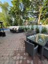 Expansive paver patio with a white privacy fence and mature trees