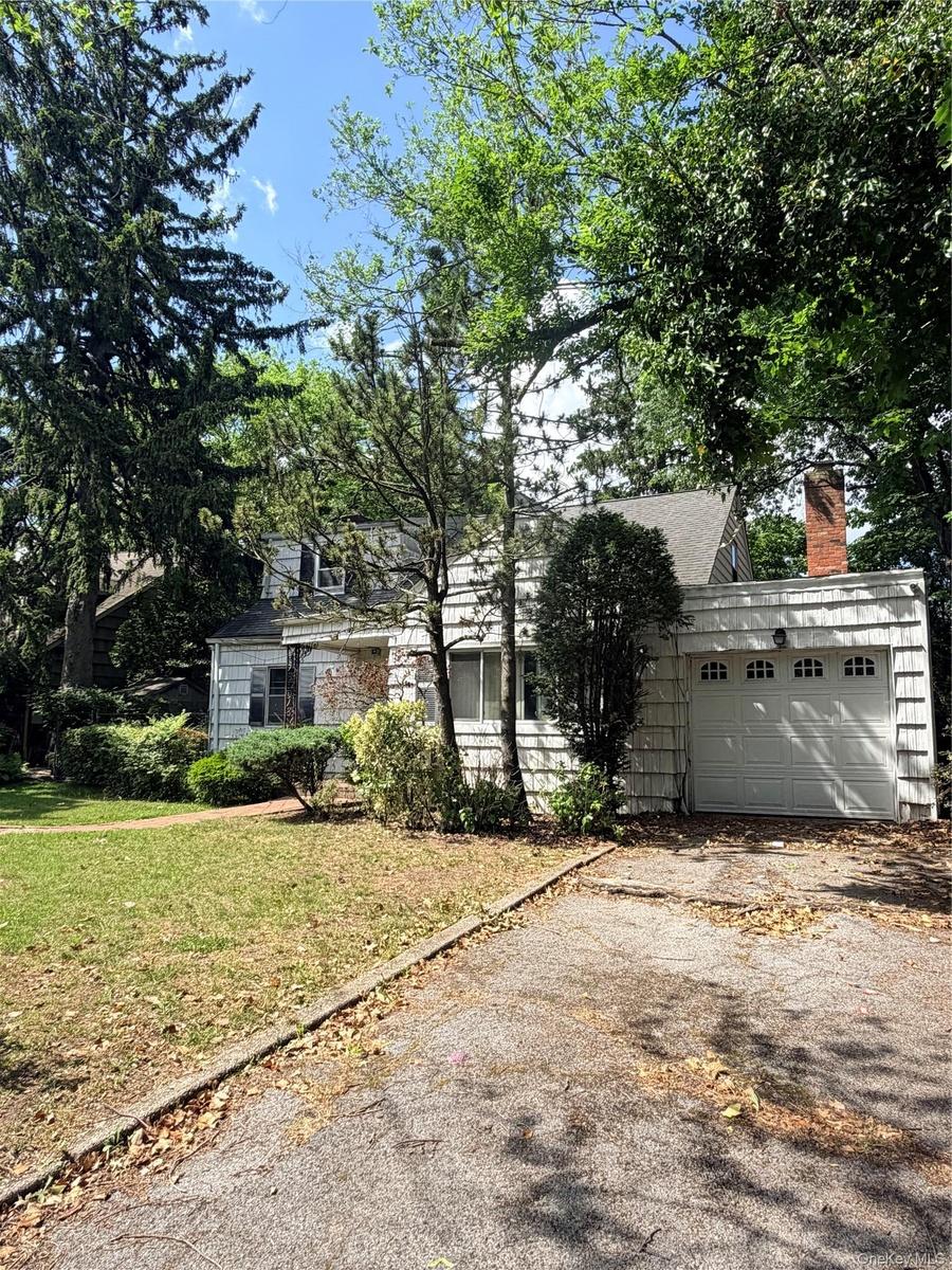 White siding exterior with a single-car garage featuring a paneled door