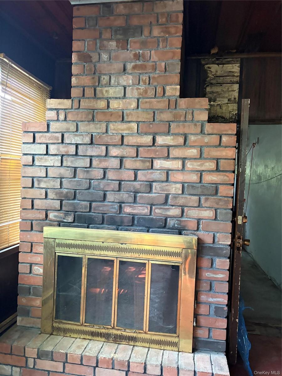Brick fireplace featuring a brass-tone firebox surround and a raised brick hearth