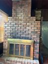 Brick fireplace featuring a brass-tone firebox surround and a raised brick hearth