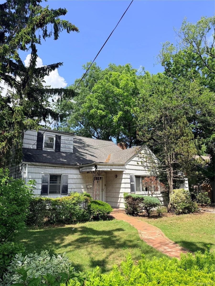 Shingled exterior home with a brick pathway