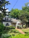 Shingled exterior home with a brick pathway