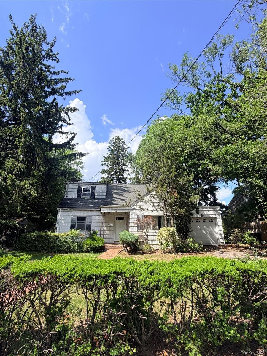 White siding exterior with a dark-shingled roof and dormer window