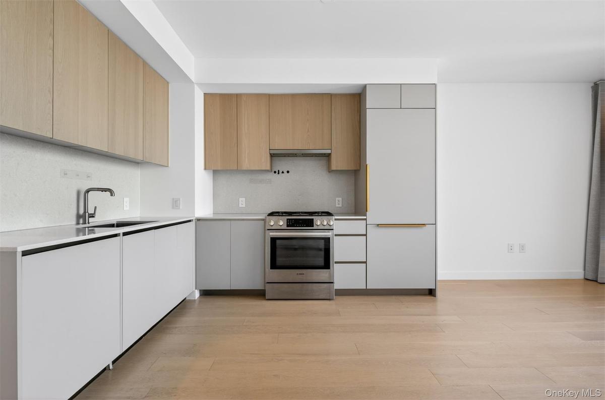 Modern kitchen with light wood-finish upper cabinetry and white lower cabinetry