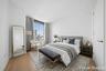 Bedroom featuring expansive window, light wood-finish flooring, and crisp white walls