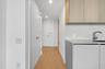Streamlined kitchen area featuring light wood-finish cabinetry, a solid surface countertop, and a contemporary sink with a gooseneck faucet