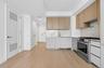 Modern kitchen featuring wood-finish upper cabinetry, white lower cabinetry, and stainless steel appliances