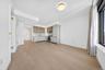 Open-concept living area featuring light wood-finish flooring, a modern kitchen with integrated appliances, upper wood-tone cabinetry, lower grey cabi