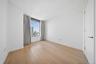 Room featuring wood-finish flooring, a full-height window with gray drapery, high ceilings, white walls, and a white interior door with brass hardware