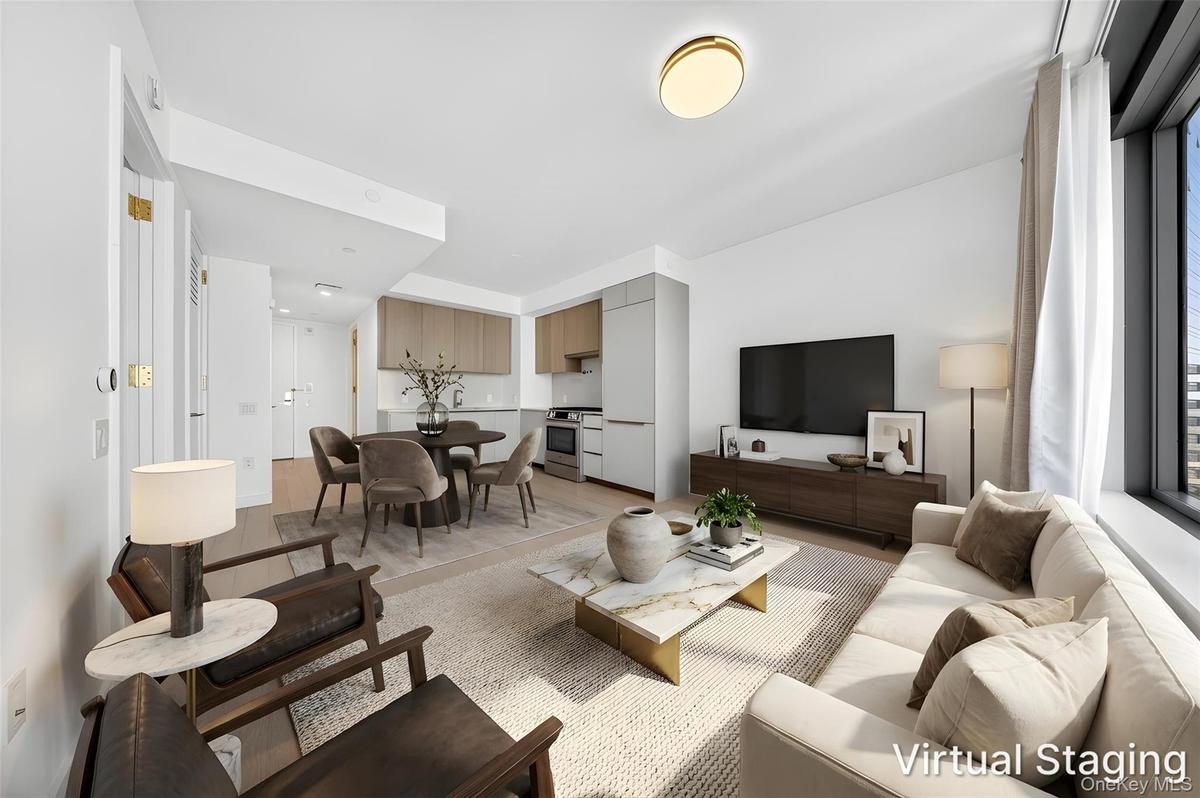 Open-concept living space featuring wood-finish flooring, a contemporary kitchen with light wood-finish cabinetry, and a dining area