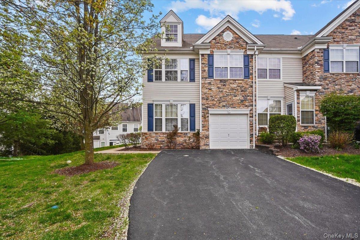 Multi-level townhome featuring stone and siding facade, an integrated garage, and a paved driveway