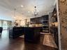 Kitchen featuring dark wood-finish flooring, two central islands, dark cabinetry, stainless steel appliances, and recessed lighting