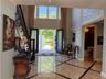 Two-story foyer featuring marble flooring with contrasting inlay, a dark wood staircase with ornate newel post, and decorative wall panels
