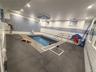 Indoor swimming pool featuring blue mosaic tile walls and dark gray floor tile