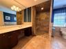 Spacious bathroom featuring a large vanity with ample countertop space, a walk-in shower with integrated bench seating, and patterned floor tiling