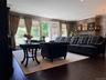 Living area featuring rich wood-finish flooring, a stone-faced fireplace with a mantel, recessed lighting, crown molding, and direct access to an exte