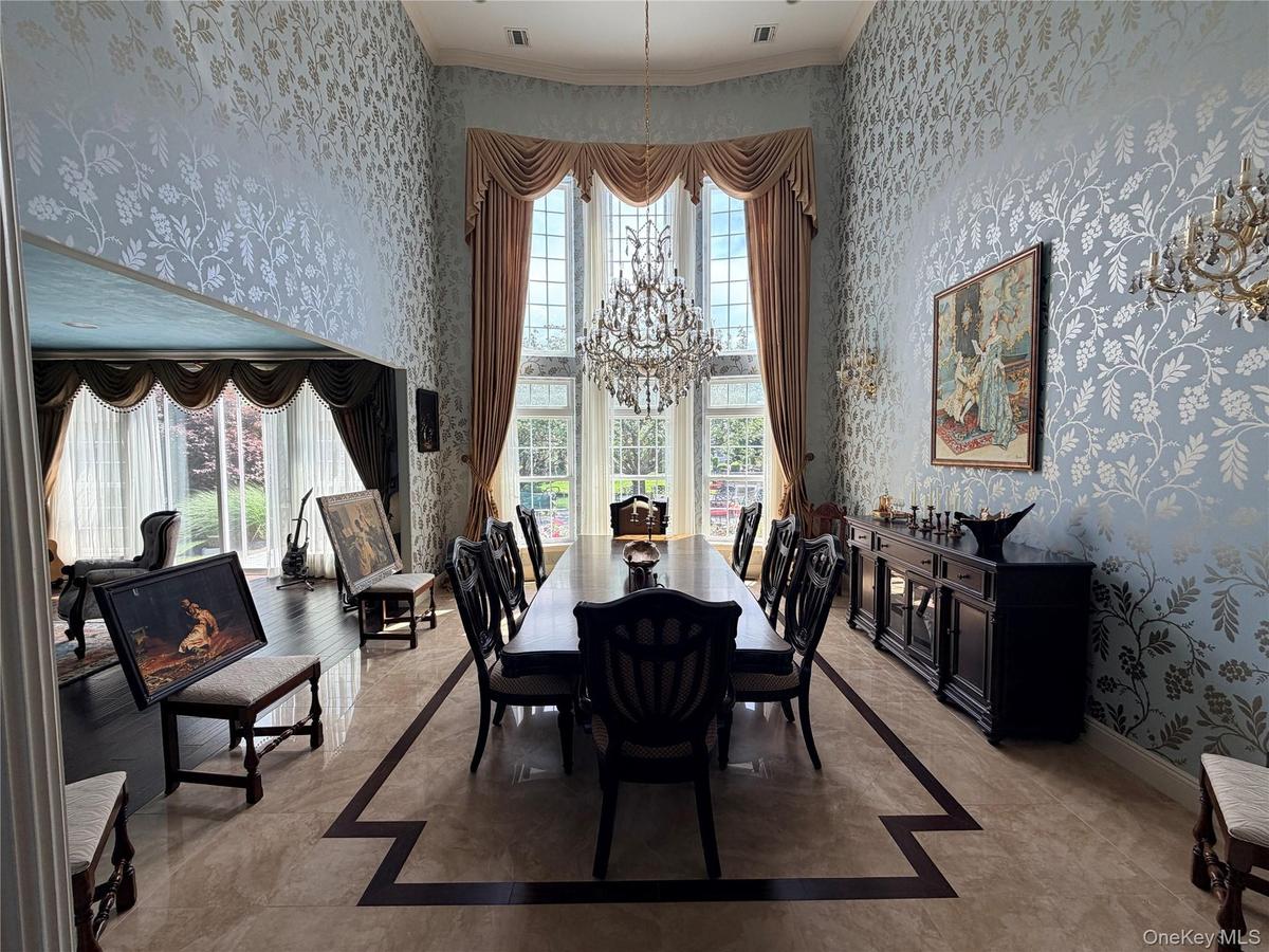 Dining space featuring a double-height ceiling, large windows with drapery, and patterned wallpaper
