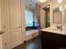Bathroom featuring a double vanity with an integrated white sink and chrome faucet, white countertop, and dark wood-finish cabinetry