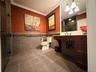 Spacious bathroom featuring large format floor tiles, a dark wood-finish vanity with countertop, and a walk-in shower with glass enclosure