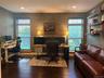 Room featuring dark wood-finish flooring, textured wall covering, recessed lighting, and two windows with blinds