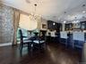 Open-concept space featuring dark wood-finish flooring, a kitchen with dark cabinetry, a breakfast bar, and a dining area with a chandelier