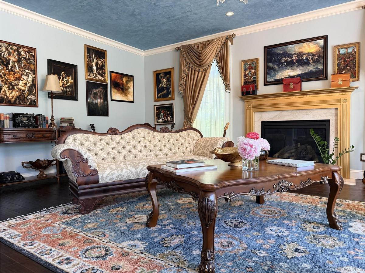 Living area featuring a detailed fireplace with a gold-finished mantel, a light blue wall color, and crown molding