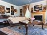 Living area featuring a detailed fireplace with a gold-finished mantel, a light blue wall color, and crown molding