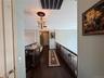 Upper-level hallway featuring dark wood-finish flooring, decorative wall paneling, and an ornate chandelier