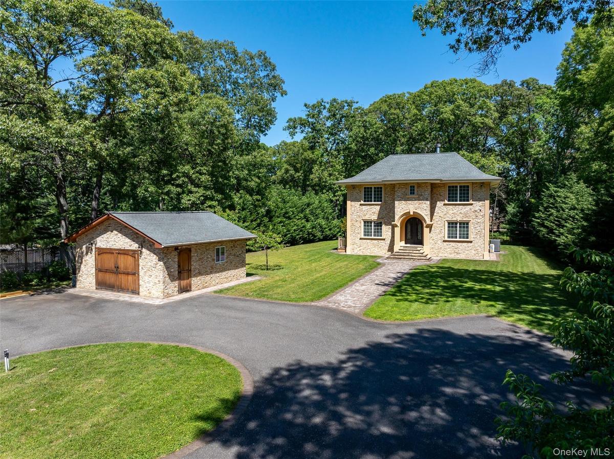 Stone-clad residence featuring a central arched entryway, multi-paned windows, and a dark shingle roof