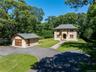 Stone-clad residence featuring a central arched entryway, multi-paned windows, and a dark shingle roof