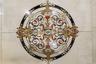 Decorative floor medallion featuring intricate scrollwork and a multi-tone palette, set into light-toned tile flooring