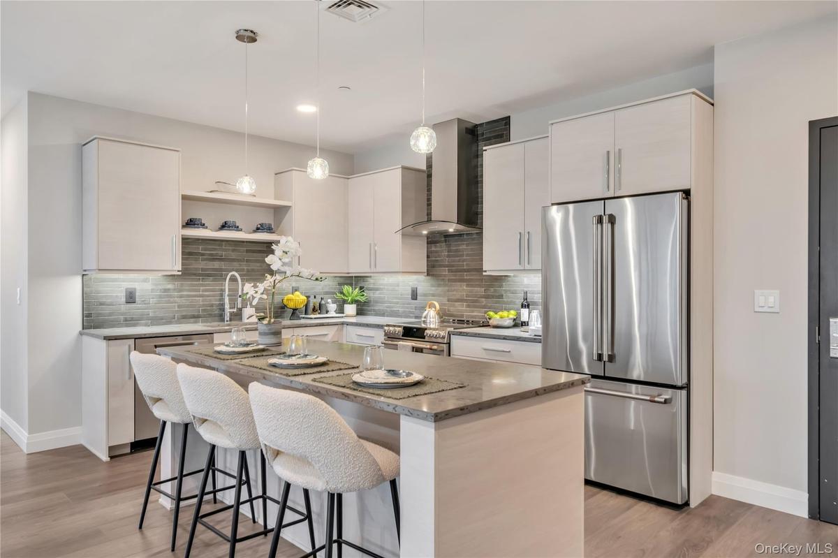 Kitchen featuring a breakfast bar, baseboards, wall chimney exhaust hood, a sink, and appliances with stainless steel finishes