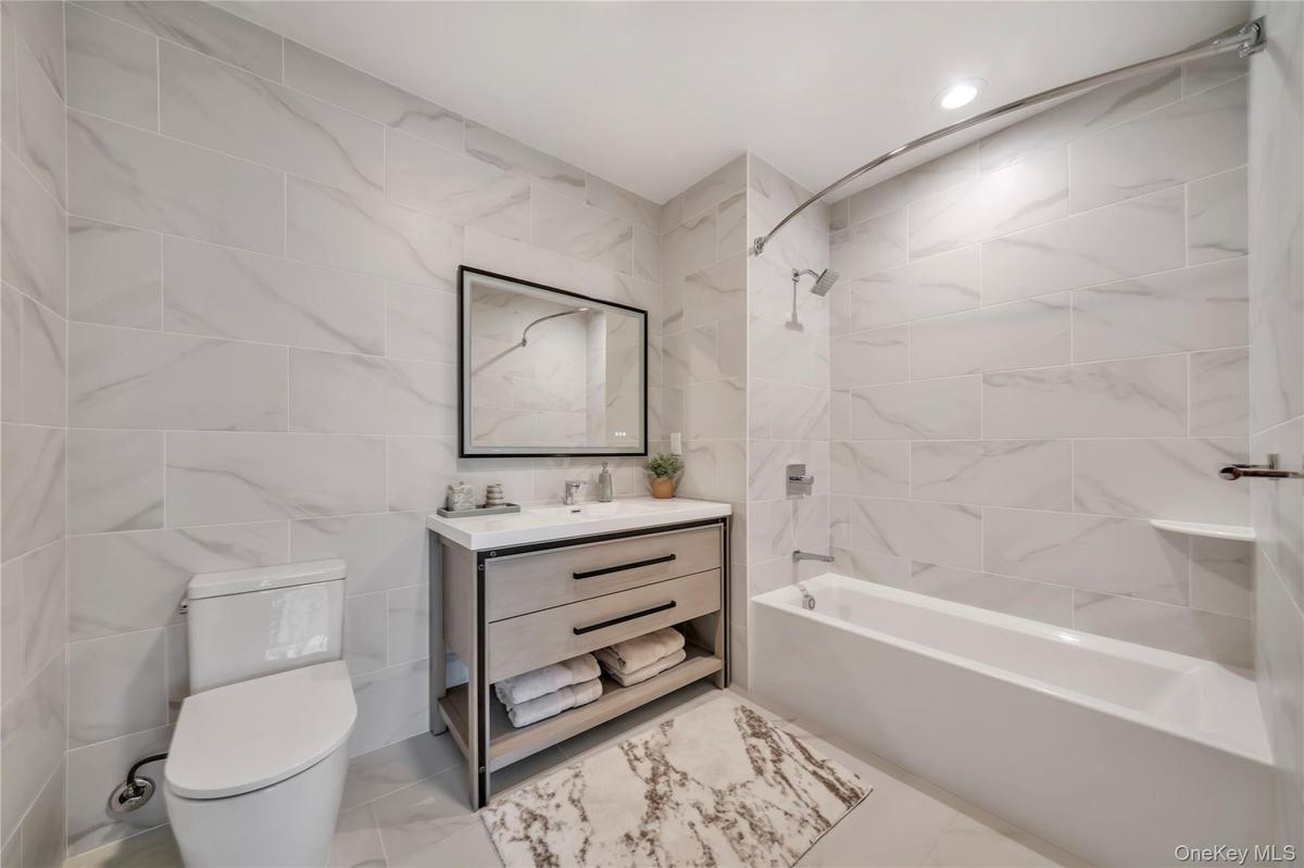 Bathroom featuring tile walls, vanity, toilet, and shower / washtub combination
