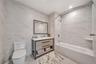 Bathroom featuring tile walls, vanity, toilet, and shower / washtub combination