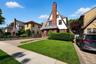 Tudor-style residence featuring a prominent brick chimney, multi-toned slate roof, and white siding with dark trim accents