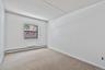 Neutral wall color, carpeted flooring, and a single window