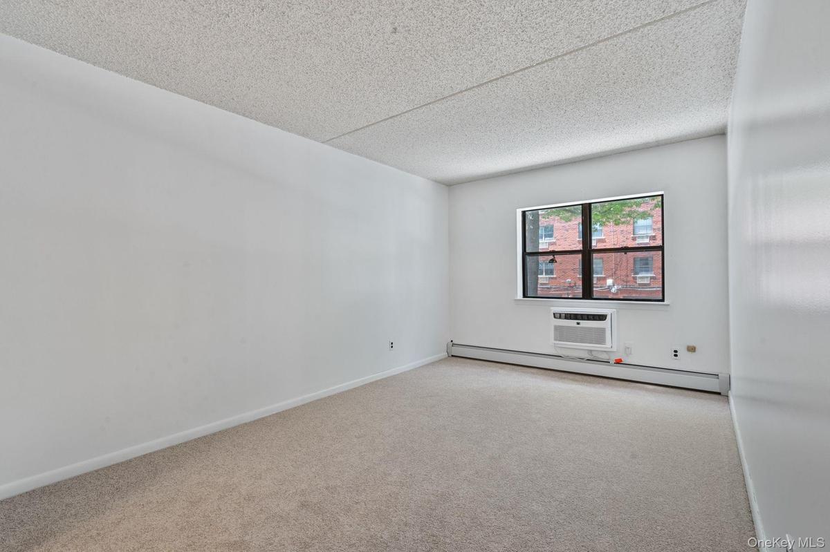 Carpeted room featuring a window with a window-mounted air conditioning unit