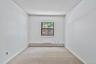 Neutral wall paint with textured ceiling, light-colored carpet flooring, and a single window offering exterior views