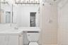 Bathroom featuring a single vanity, integrated sink, chrome faucet, and white cabinetry