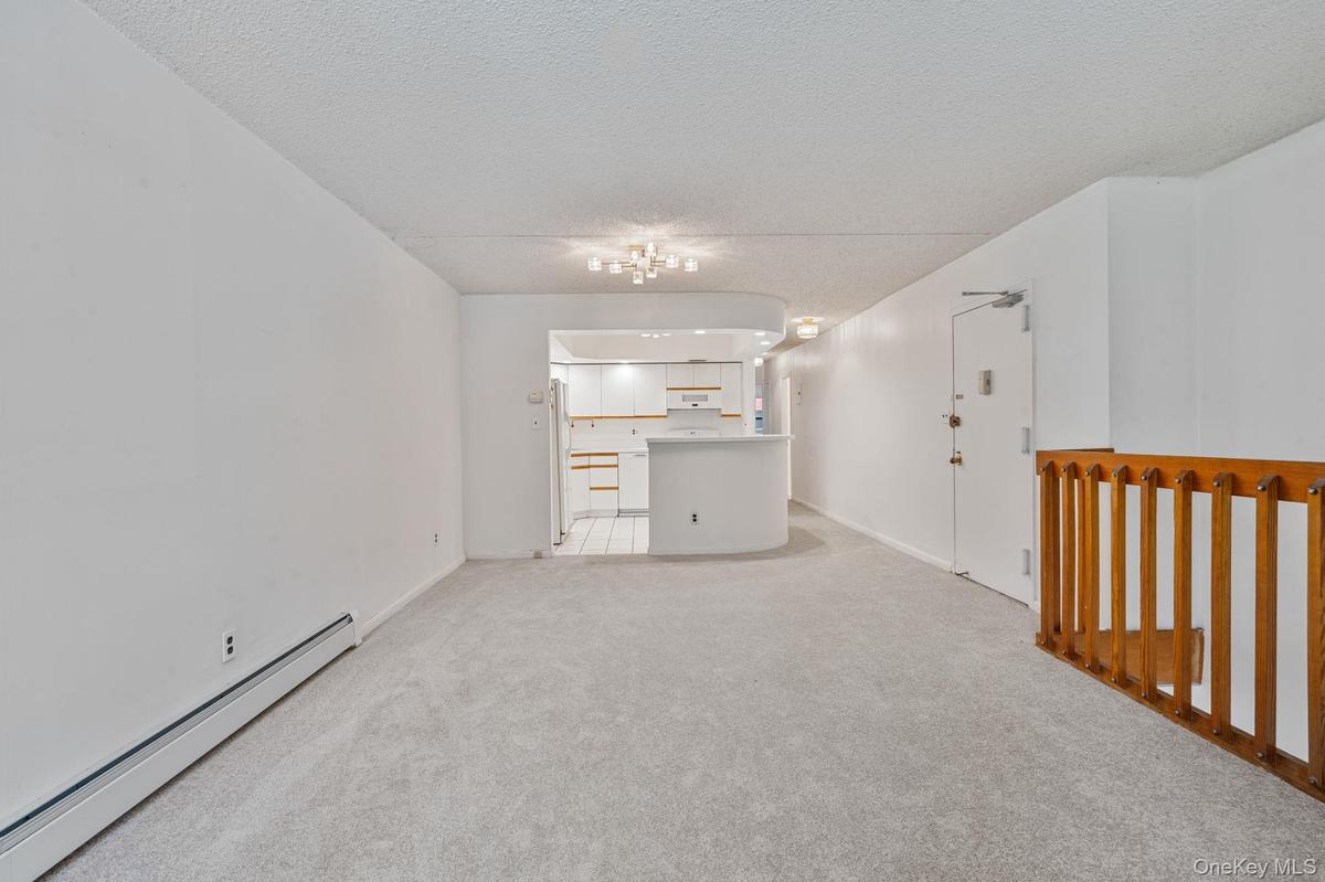 Open-concept living space featuring light gray carpeting and white walls