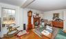 Hardwood flooring throughout a room featuring a brick fireplace with a wood mantel