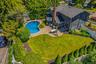 Magnificent backyard oasis featuring a pristine in-ground pool, expansive stone patio perfect for outdoor dining, and a beautifully manicured, private