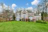 View of front of home featuring a front yard, a shingled roof, a chimney, stone siding, and brick siding