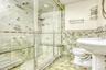 Bathroom featuring tile walls, light tile patterned flooring, a shower stall, and a wainscoted wall