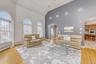 Living area with arched walkways, high vaulted ceiling, light wood-style flooring, and baseboard heating